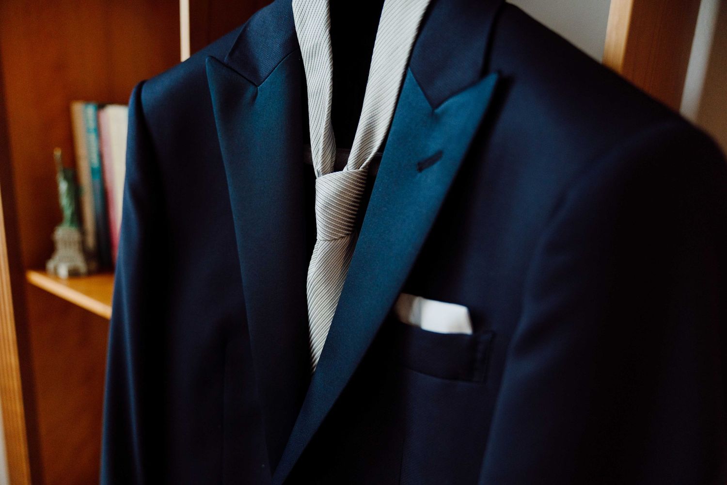 Navy blue suit jacket with teal lapels, white pocket square, and a silver tie displayed on a mannequin.