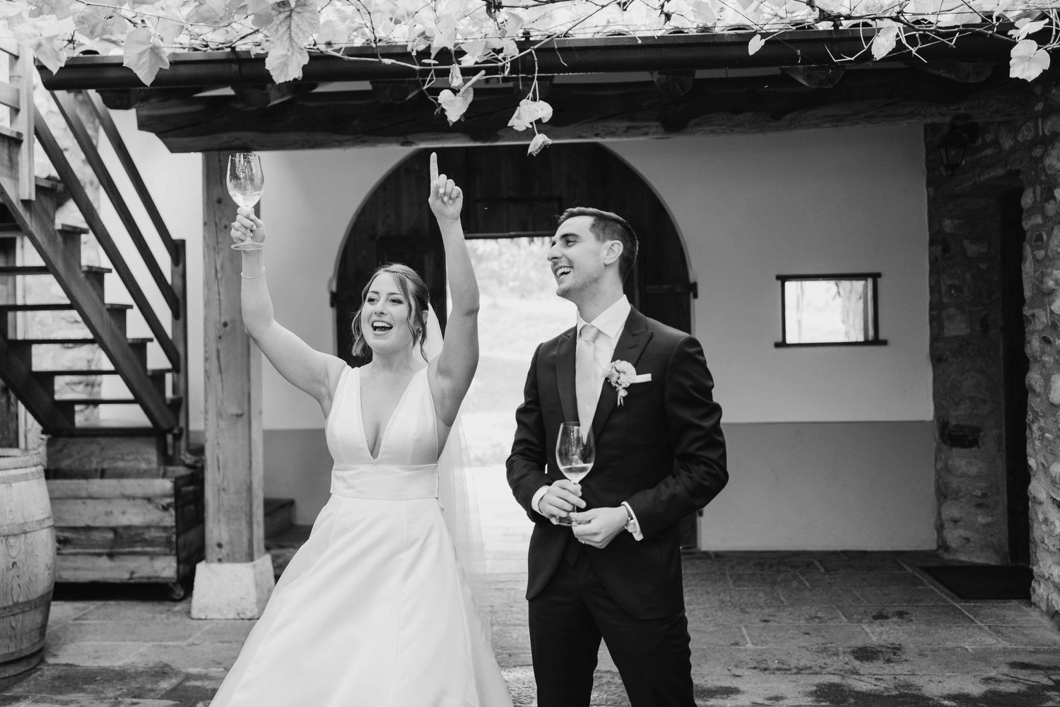 Black and white photo of a joyful bride and groom celebrating outdoors at a winery wedding venue.