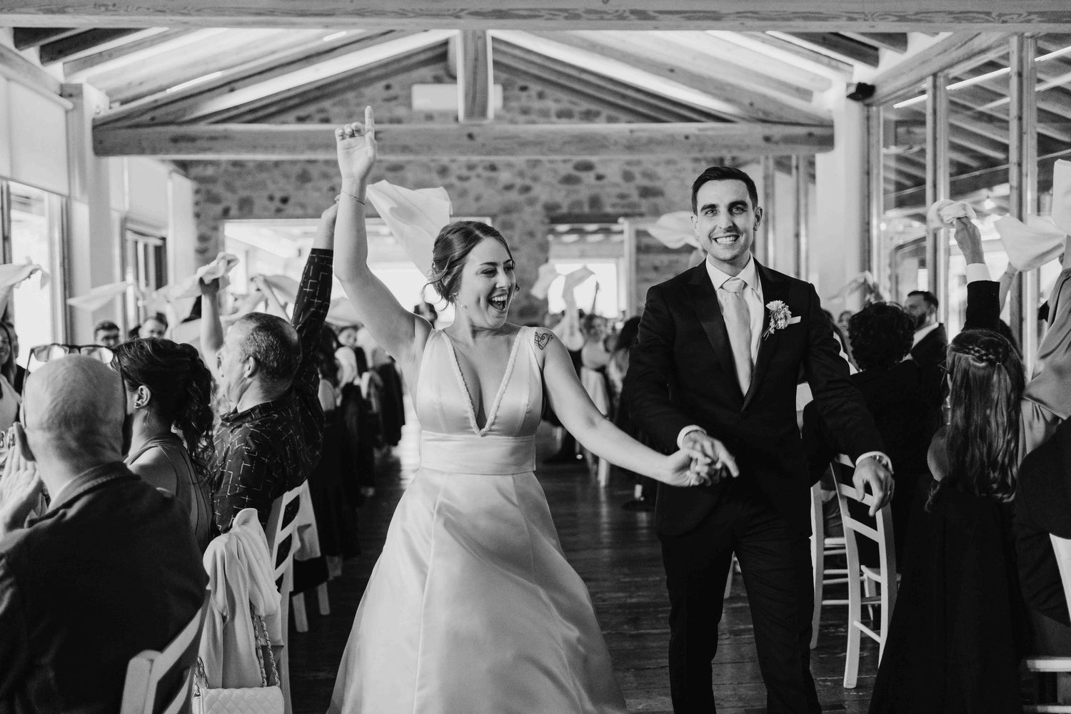Black and white photo of a joyful bride and groom making their grand entrance at their wedding reception.
