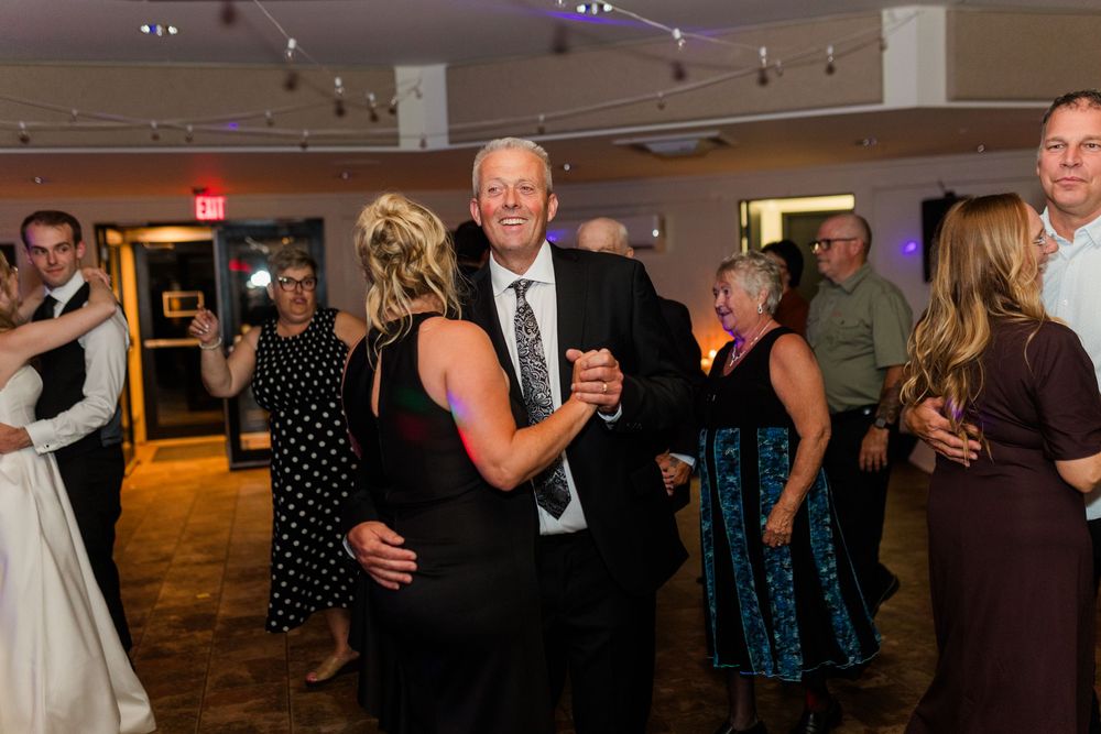 Guests dancing joyfully at a wedding reception in an elegant ballroom venue.
