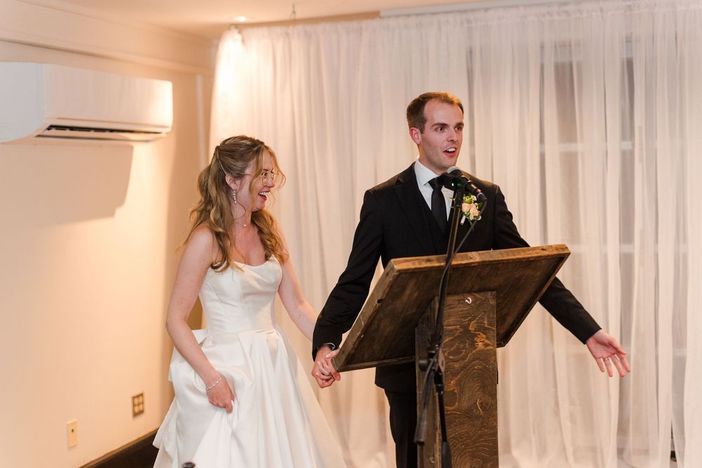 Bride and groom standing together at podium during wedding reception speech.
