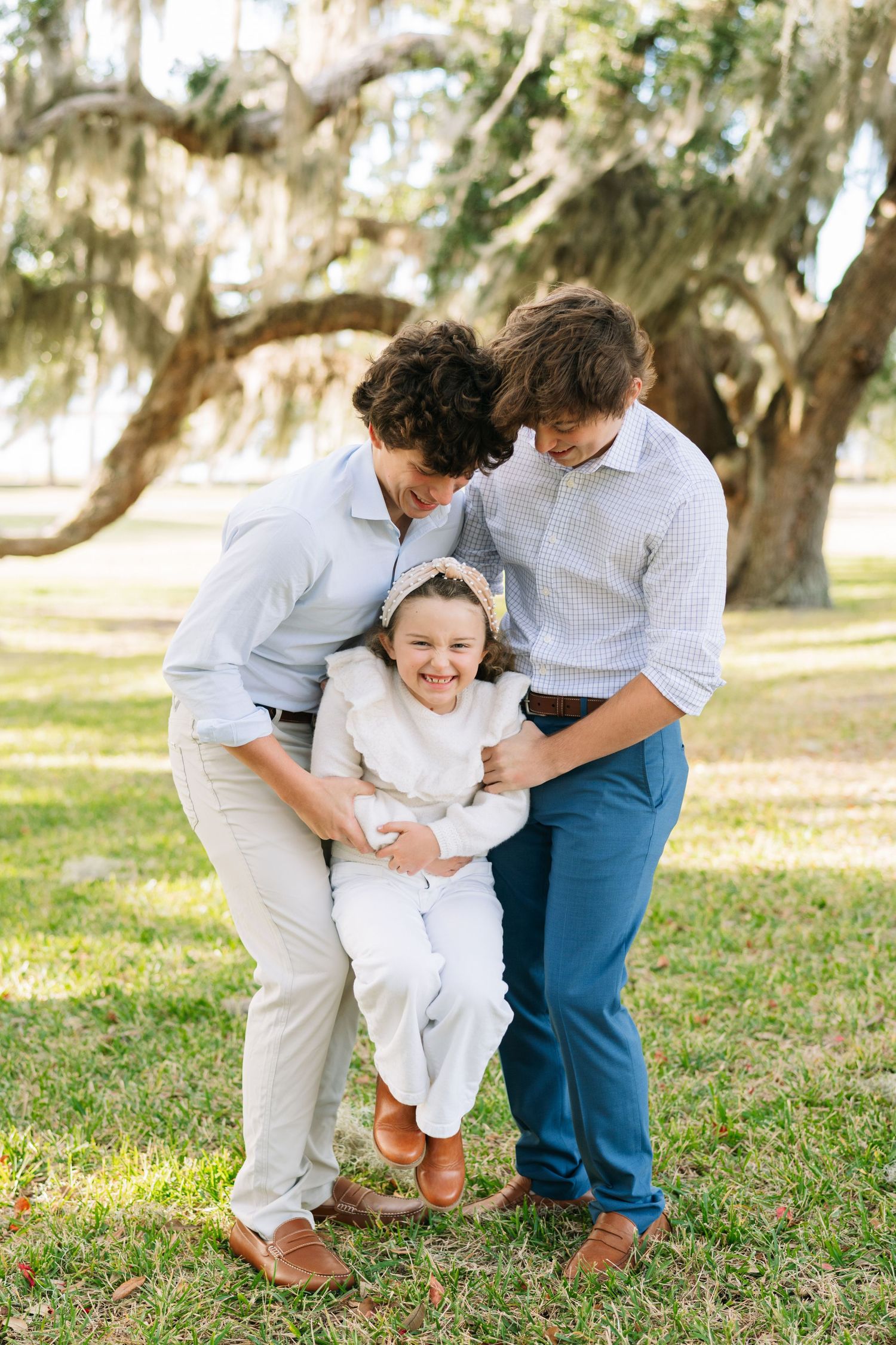 Siblings sharing a playful moment on the grass during a family photo session with Lindy Rebro Photography.