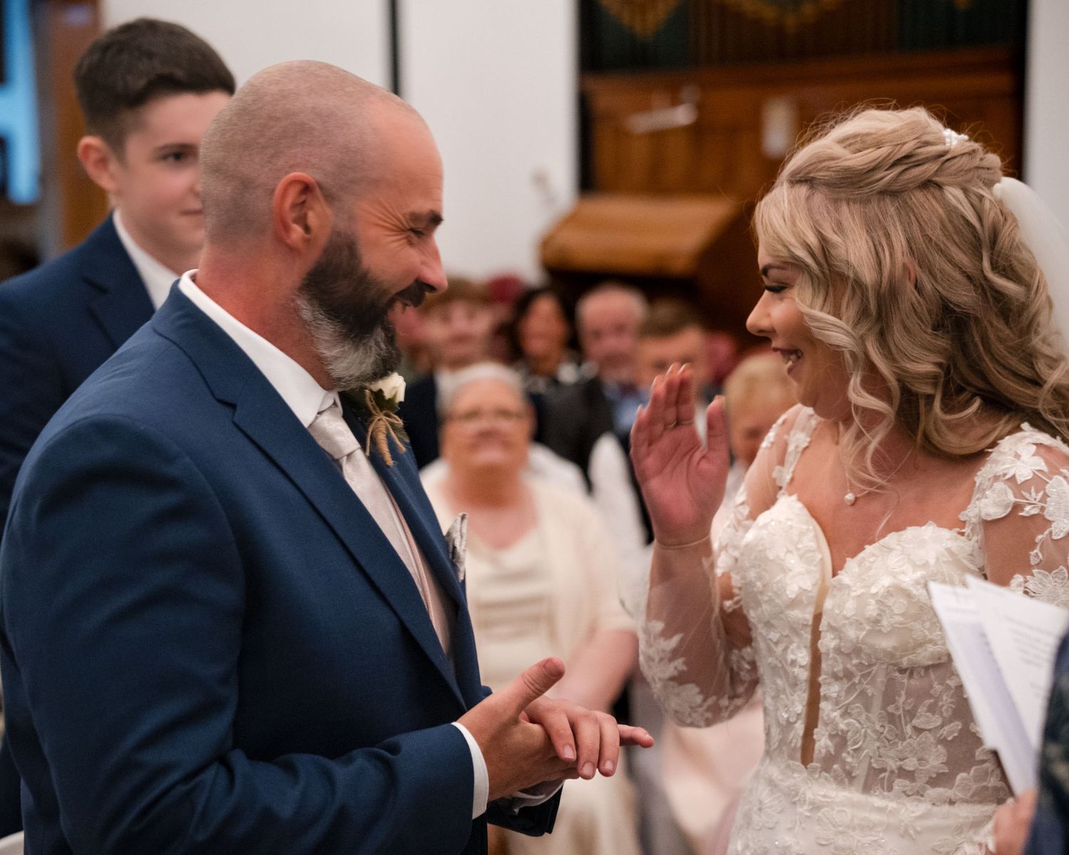 Bride and groom exchanging vows at a church wedding ceremony, smiling joyfully at each other.