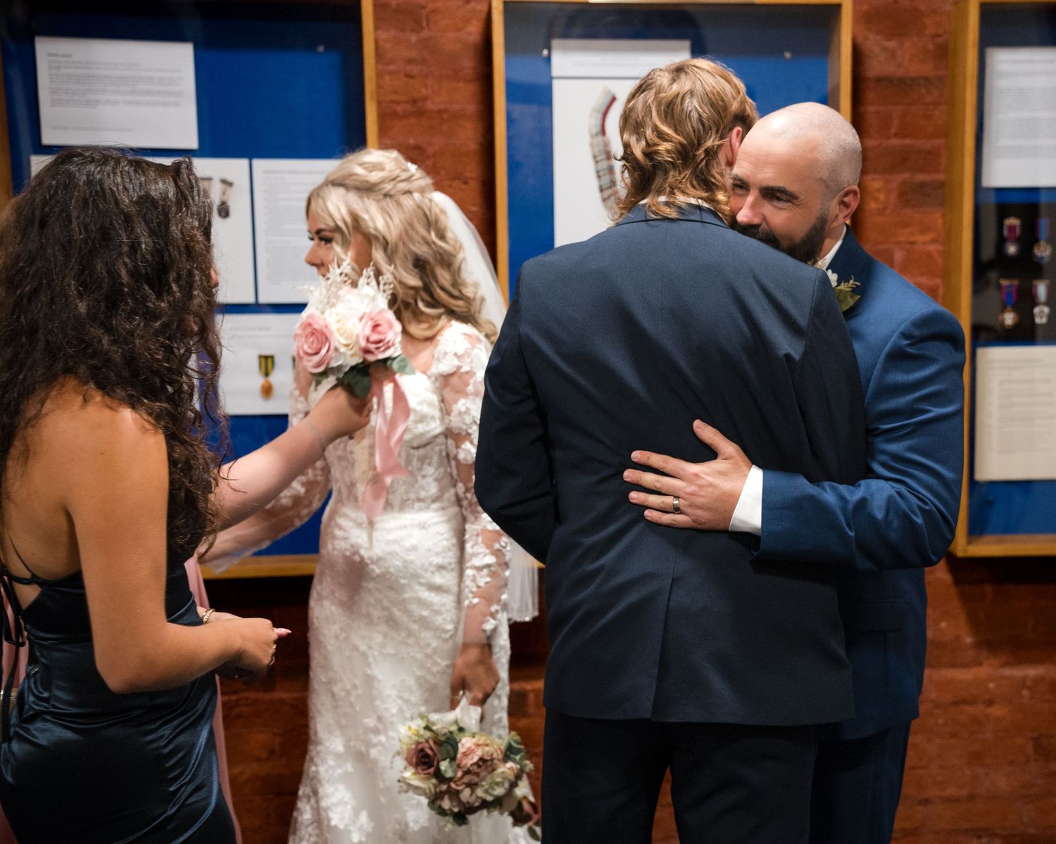 Bride and groom share a heartfelt hug with guests at an elegant wedding reception venue.