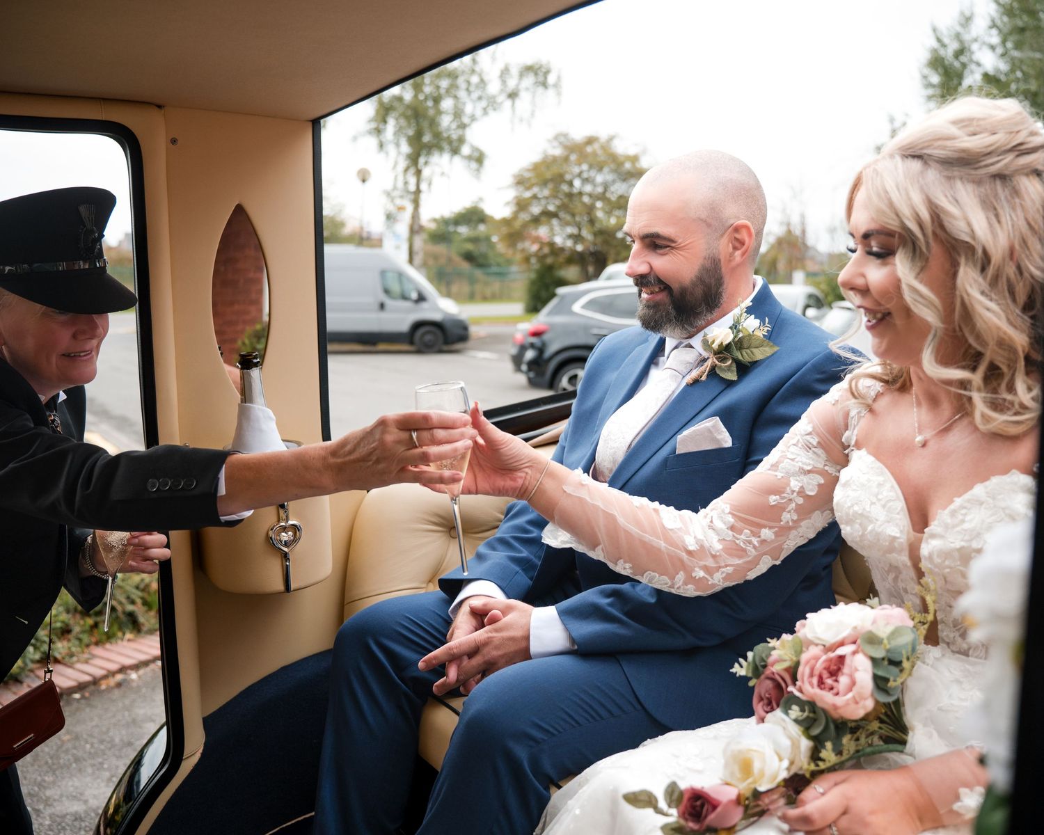 Bride and groom sitting in vintage wedding car receiving a gift from chauffeur on their special day.