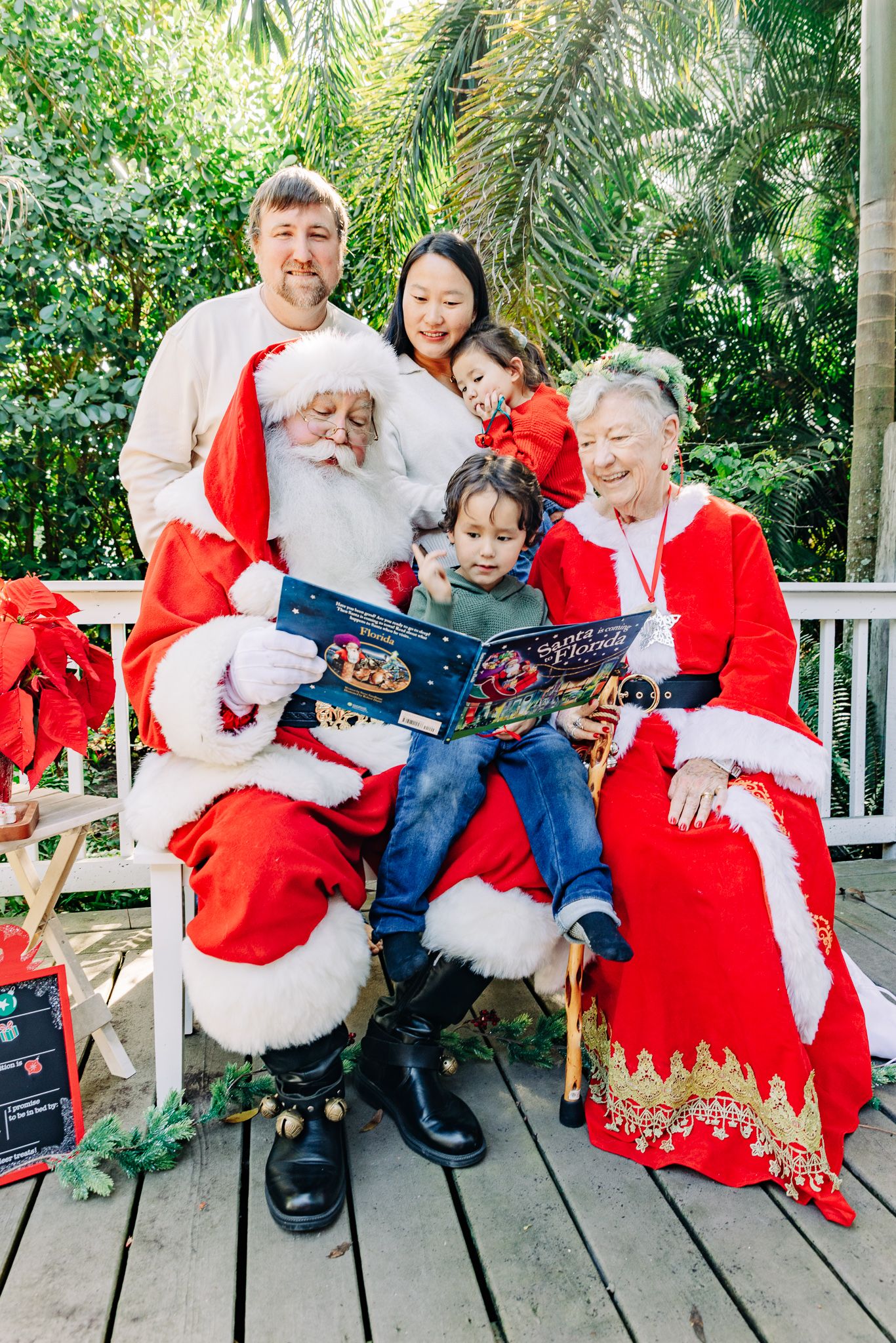 Santa and Mrs. Claus photos in Lake Worth Beach of a family reading a Christmas story together.