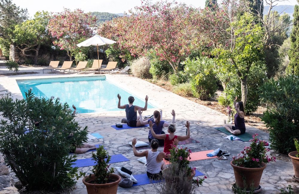 Group yoga session by the pool in Ibiza on wellbeing retreat