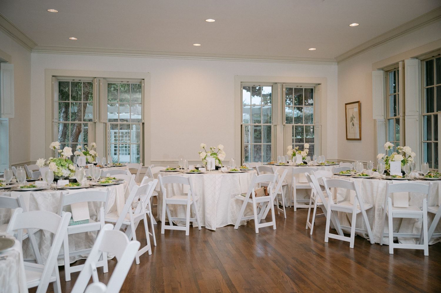 Reception space with round tables and white floral centerpieces.