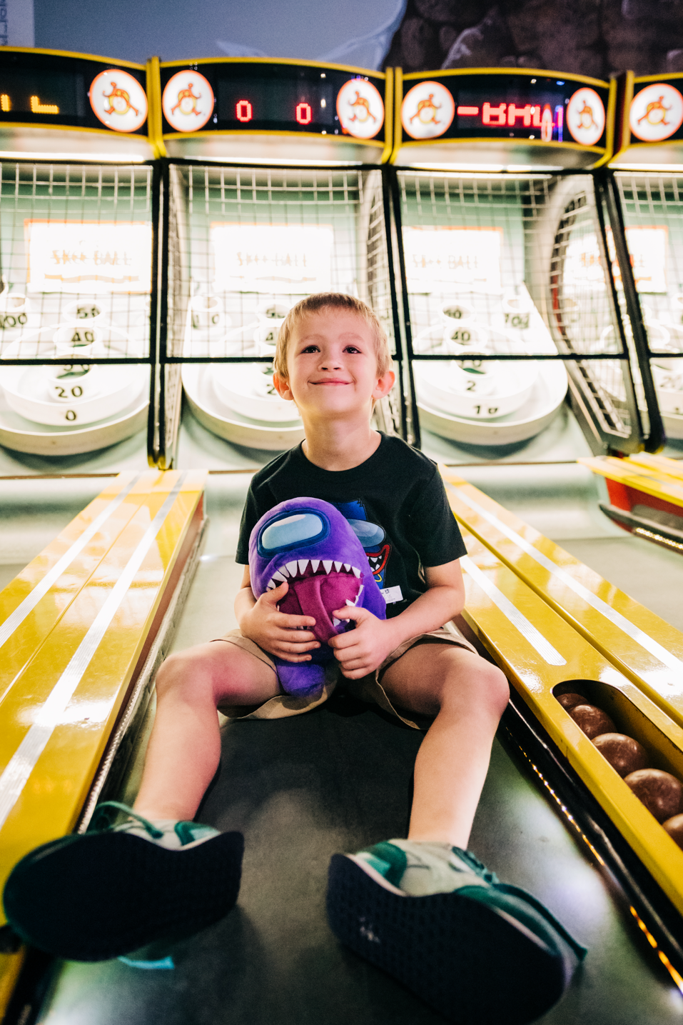 Fun Depot birthday photos in Lake Worth Beach of a boy sitting at the skee-ball lanes with his arcade prize.