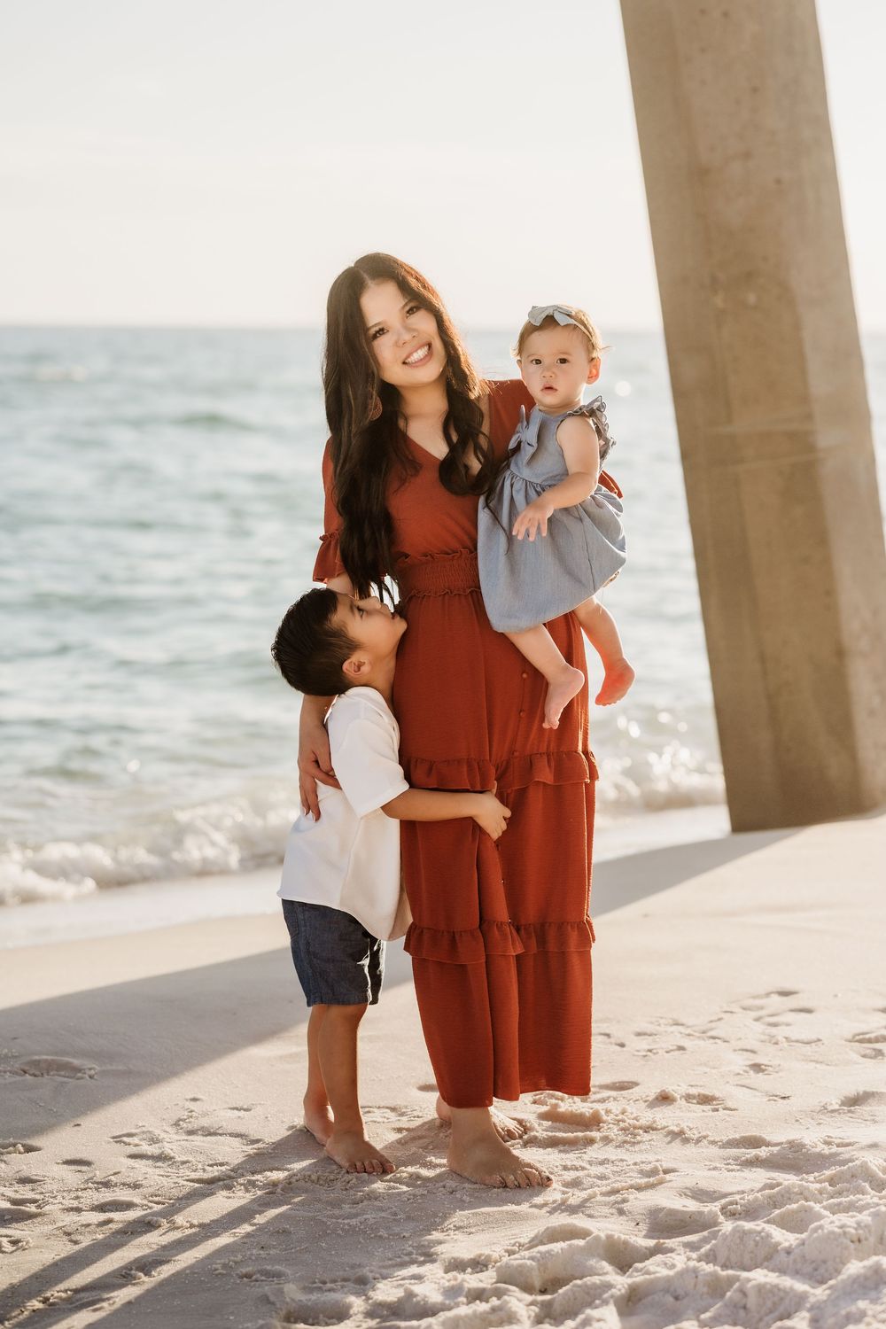 Mother holding her daughter while her son hugs her during a Pensacola Beach family session