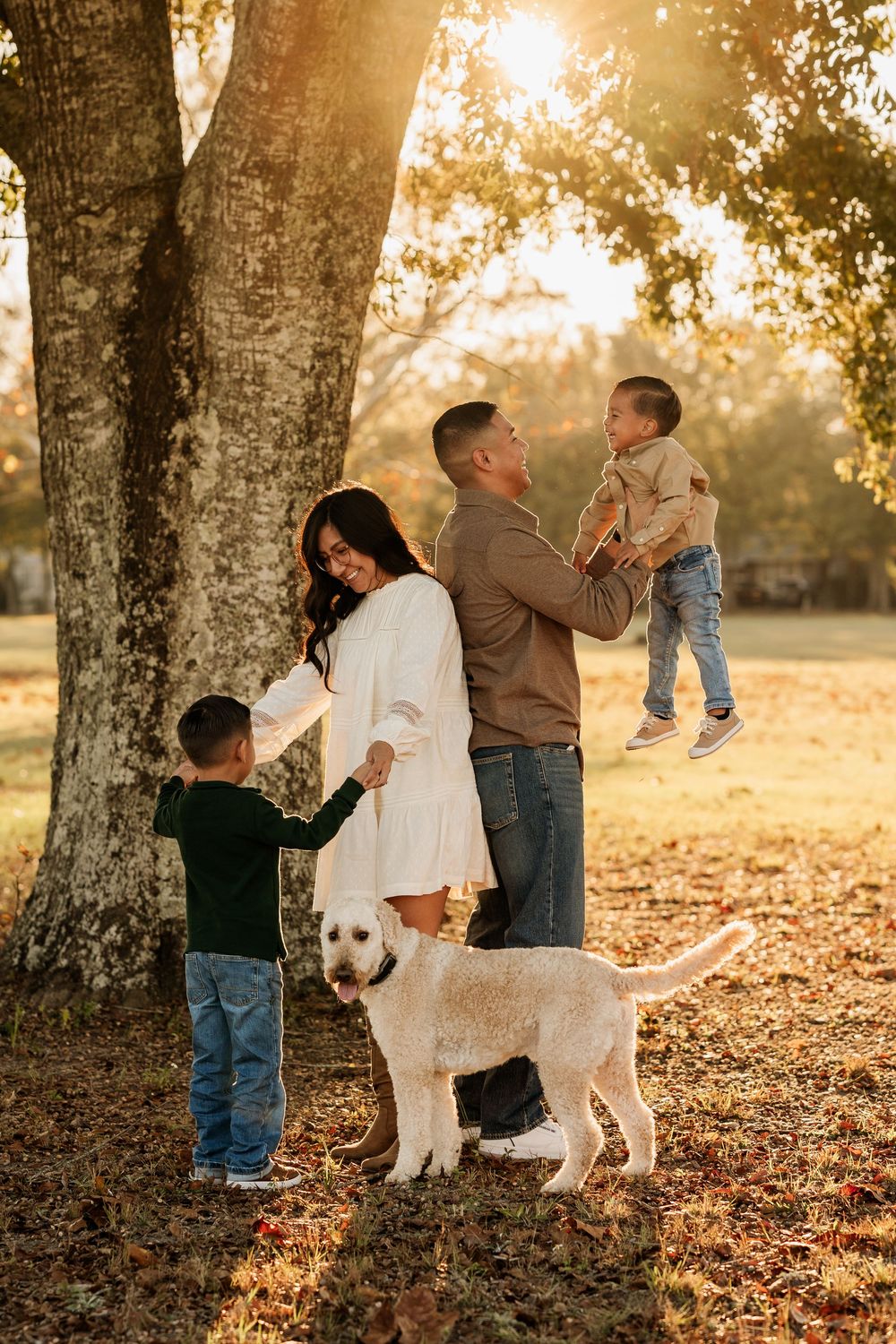 Parents and their two sons playing with their dog during a golden hour family session