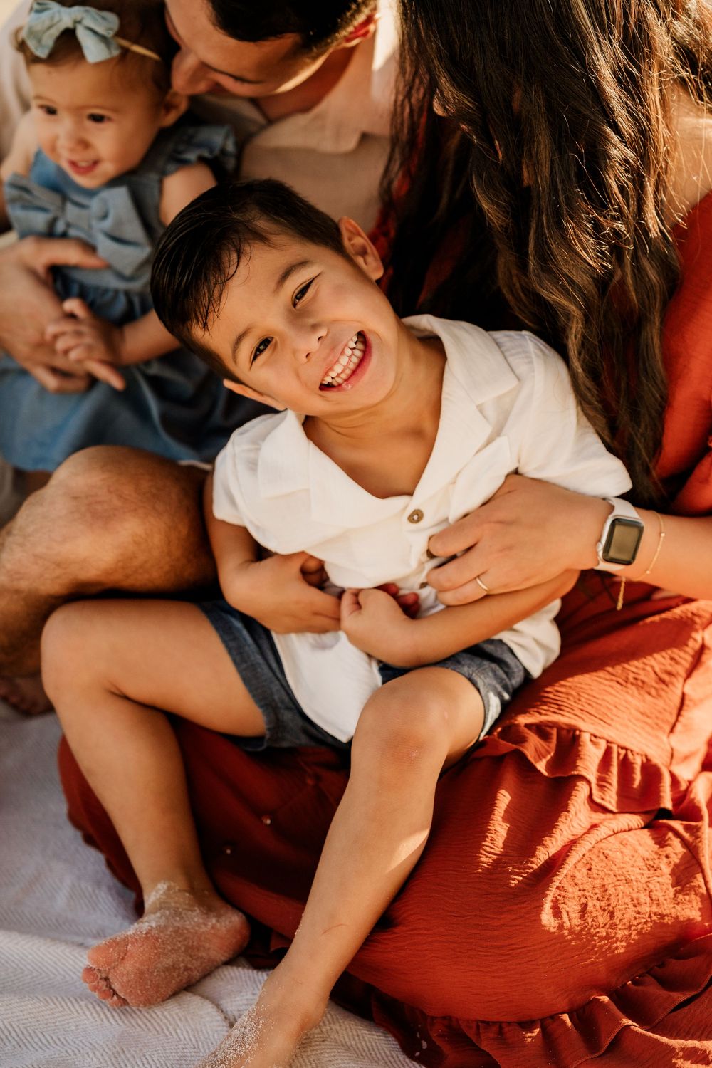 Young boy laughing with his family during a candid Pensacola Beach photo session