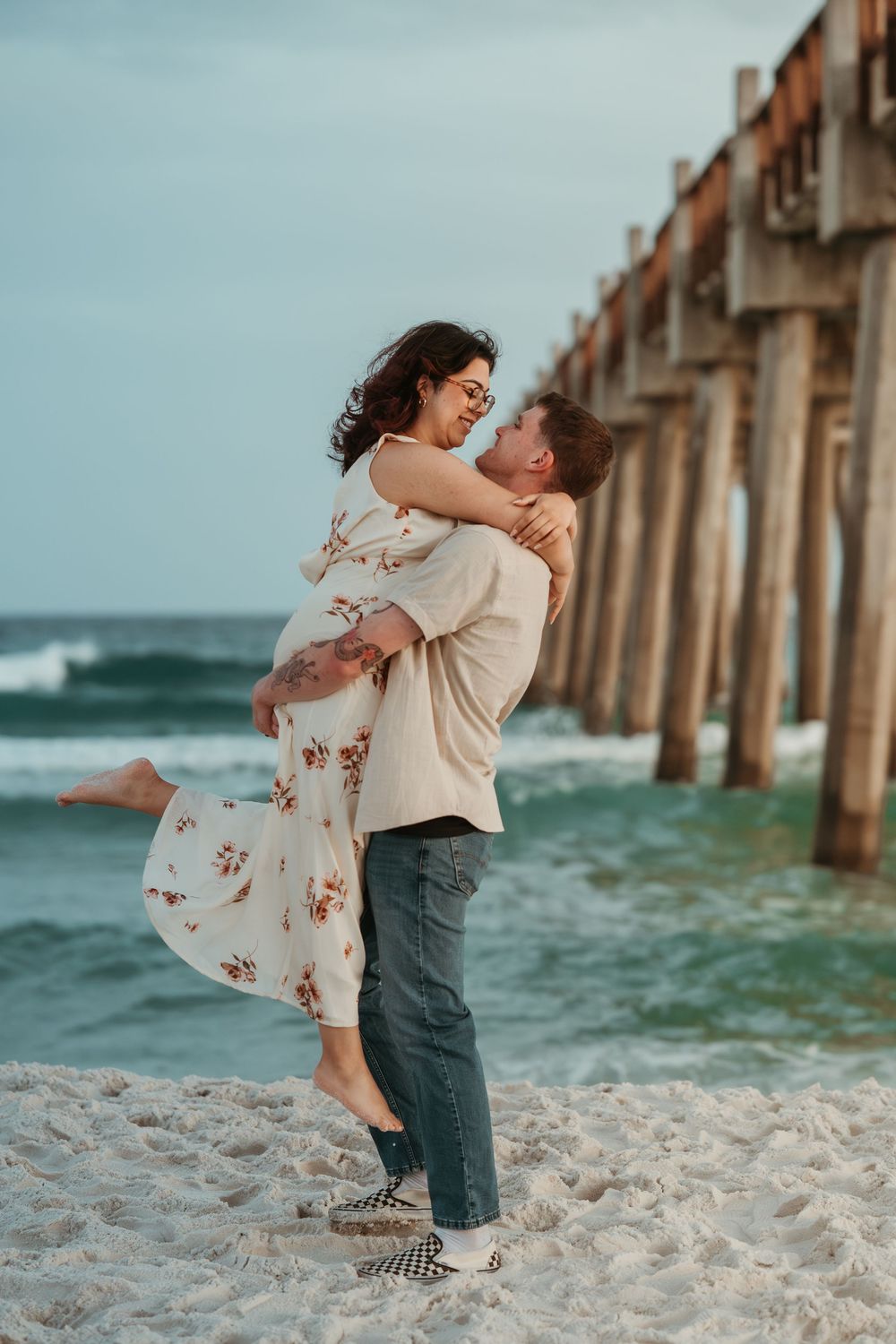Couple laughing and embracing beside the pier on Pensacola Beach