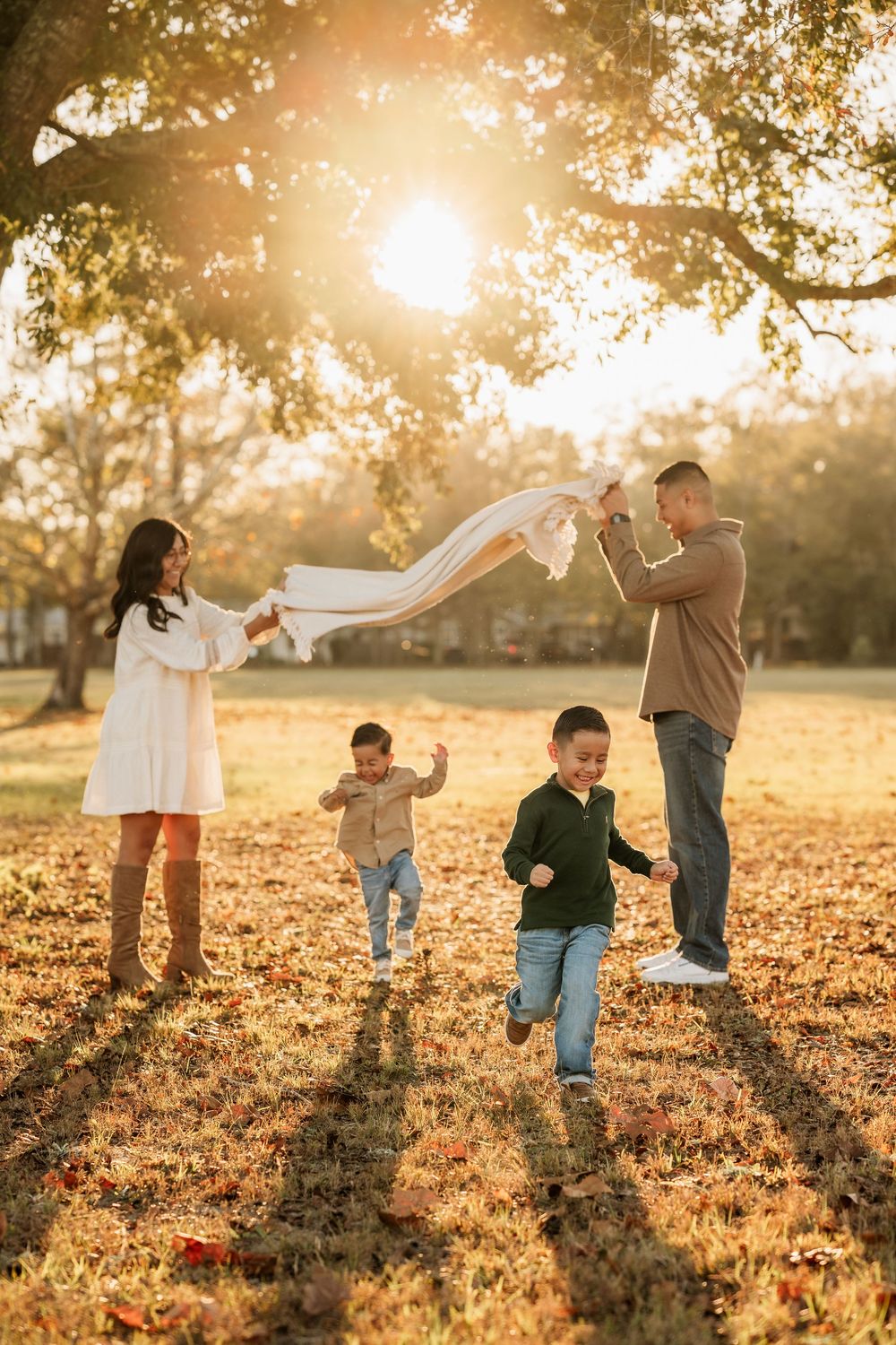 Two young boys running while their parents play with them during a sunset family session