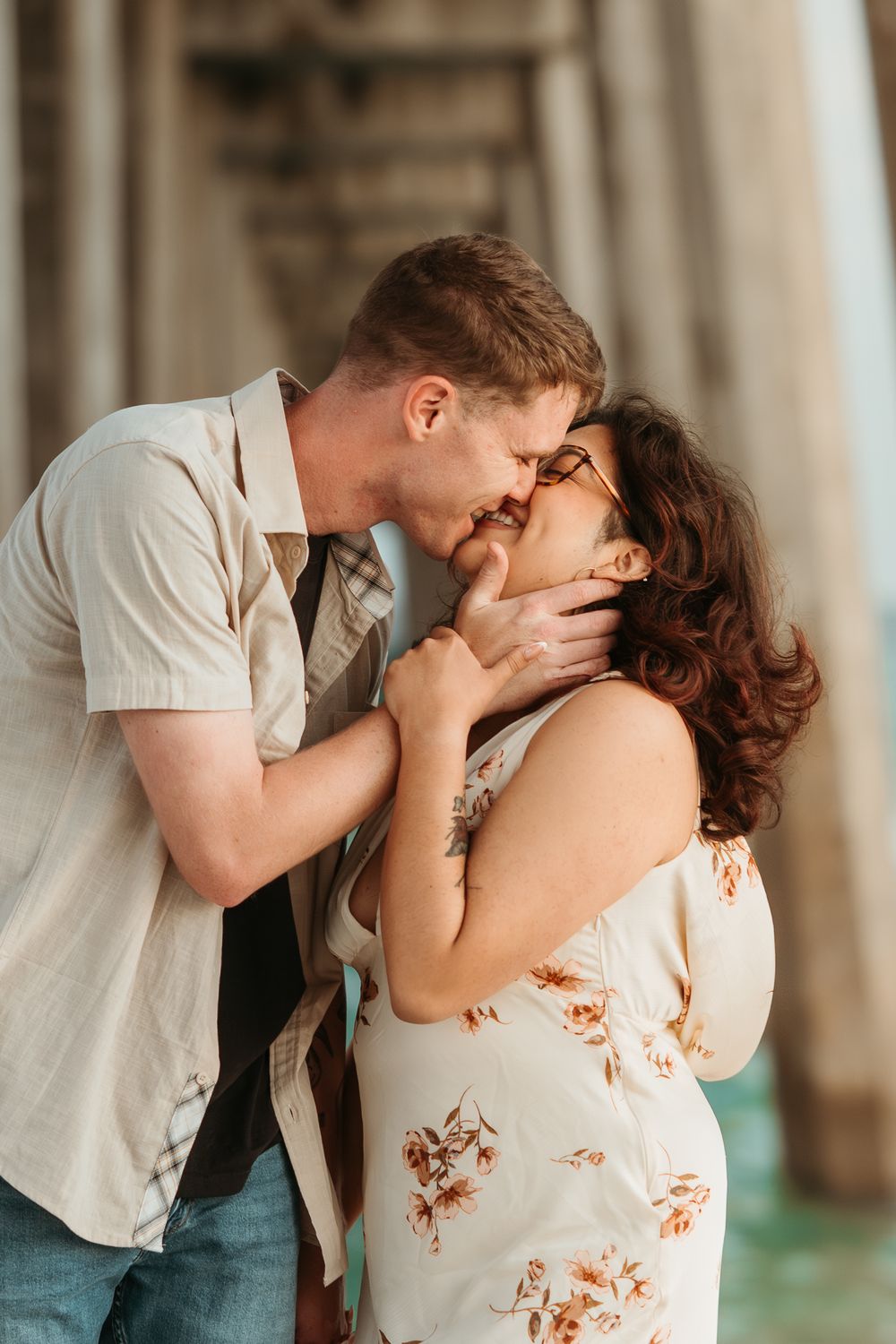 Couple laughing together beneath the pier during a Pensacola Beach photography session