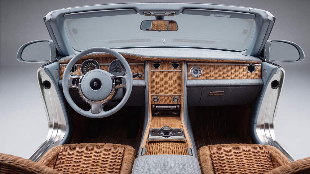 Luxurious Rolls-Royce convertible interior featuring wicker dashboard, tan leather seats, and silver steering wheel.