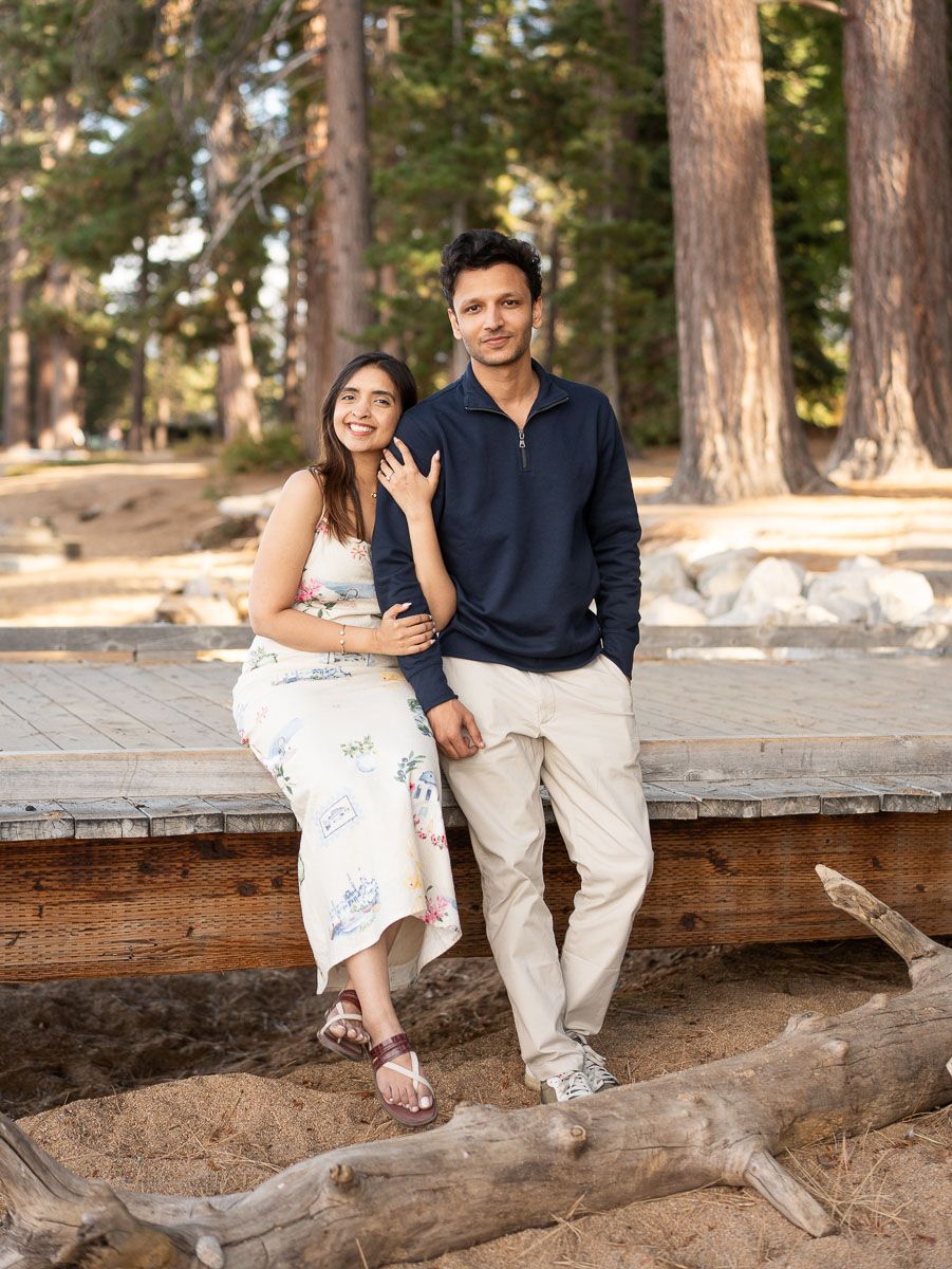 Couple embracing outdoors in autumn, surrounded by colorful orange and green foliage, in a romantic fall engagement photo.