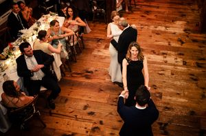 Couples dancing on a rustic wooden dance floor at an elegant wedding reception with guests seated at candlelit tables.
