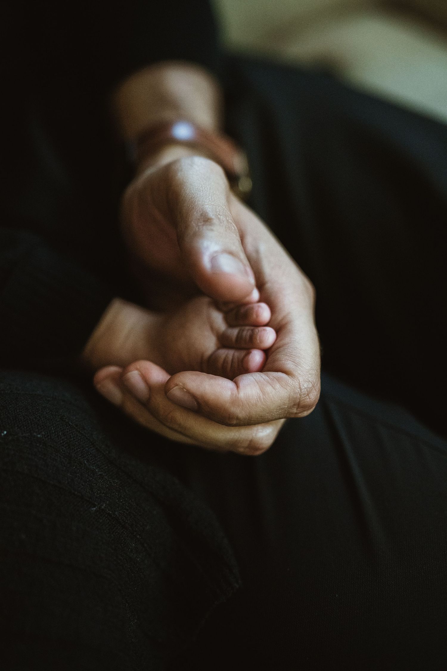 Close-up of weathered hands gently cradling a baby's tiny feet, symbolizing love and care.
