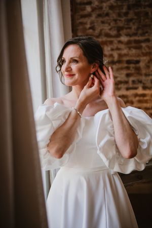 Bride putting on her earrings while getting ready for the ceremony.