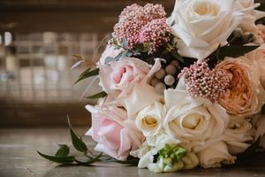 Close-up of a pastel wedding bouquet featuring pink roses and greenery.