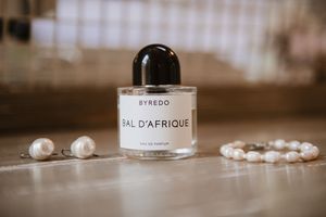 Detail shot of Byredo Bal d'Afrique perfume bottle and pearl bridal jewelry.