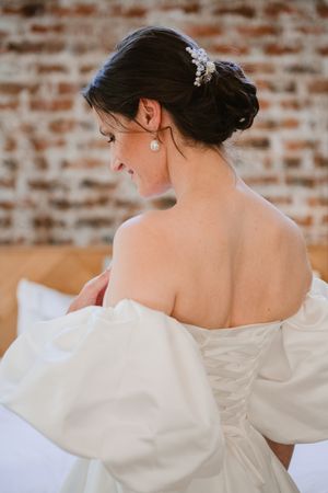 Back view of the bride showcasing the details of her off-the-shoulder wedding gown.