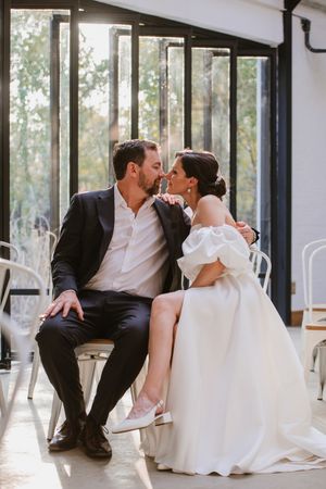 Groom kissing the bride on the cheek while seated in the venue