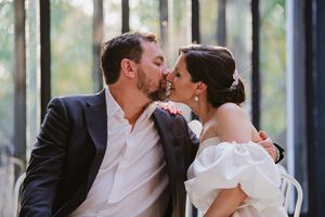 Couple sitting on a bench inside the glasshouse, looking lovingly at each other.