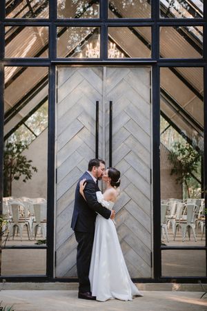 Couple standing together in the doorway of the modern glass venue.
