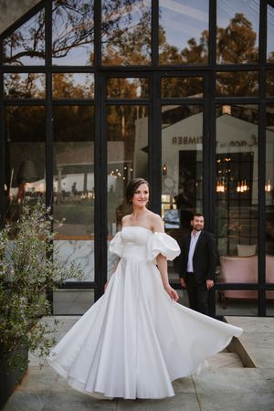 Cinematic wide shot of the couple at the wedding venue entrance.