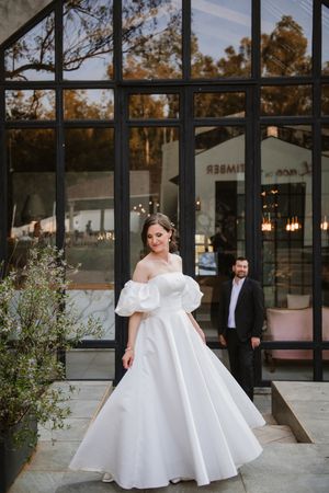 Cinematic wide shot of the couple at the wedding venue entrance.