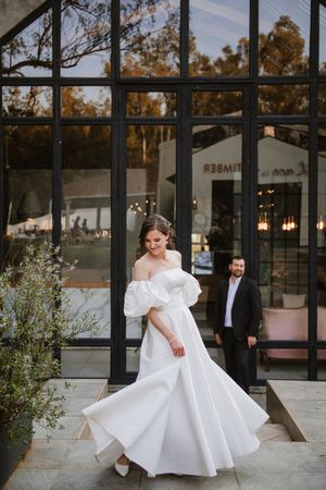 Cinematic wide shot of the couple at the wedding venue entrance.