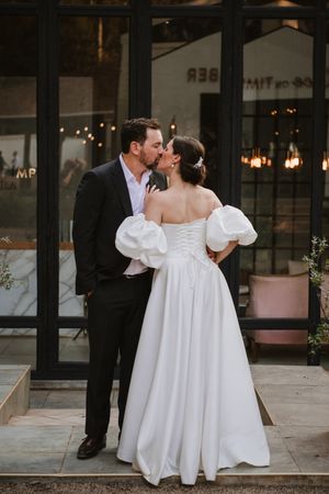 Newlyweds kissing on the steps of the white chapel venue.