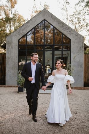 Couple walking hand-in-hand down a path outside the venue.