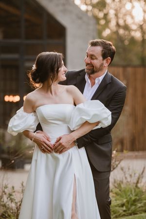 Bride and groom holding hands and looking at each other in the venue entrance.