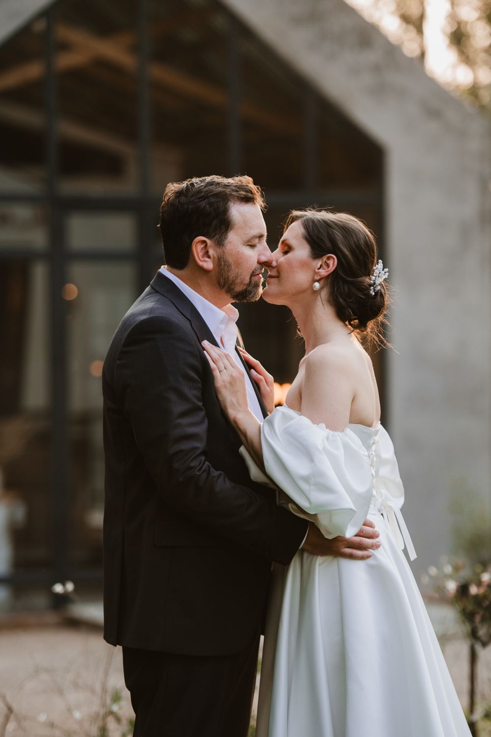 Bride and groom kissing during a candid outdoor photoshoot moment.