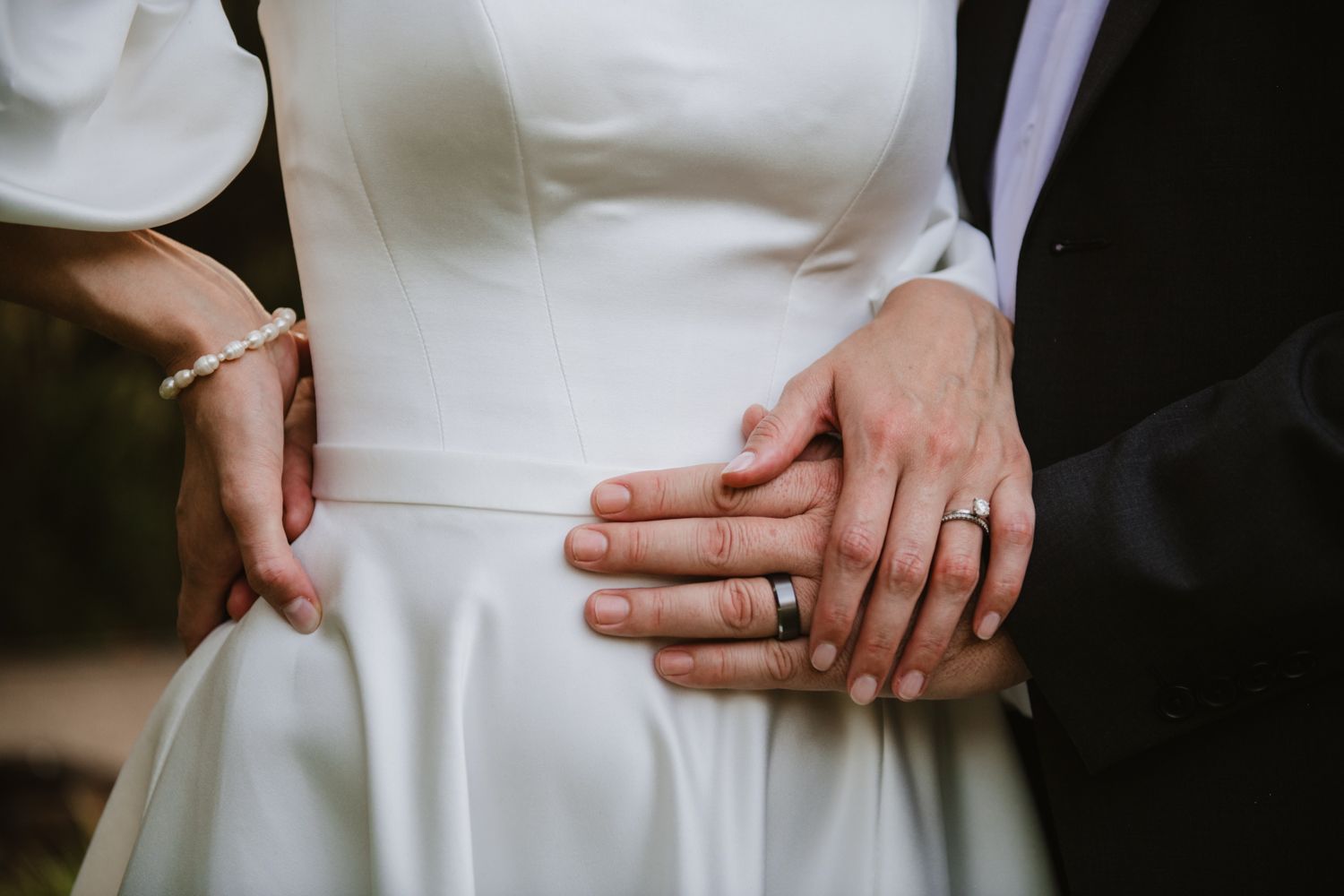 Close-up of the groom holding the bride, showing ring details.