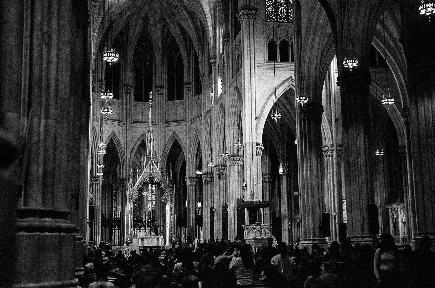 Interior of gothic cathedral with high vaulted ceilings and crowds of visitors.