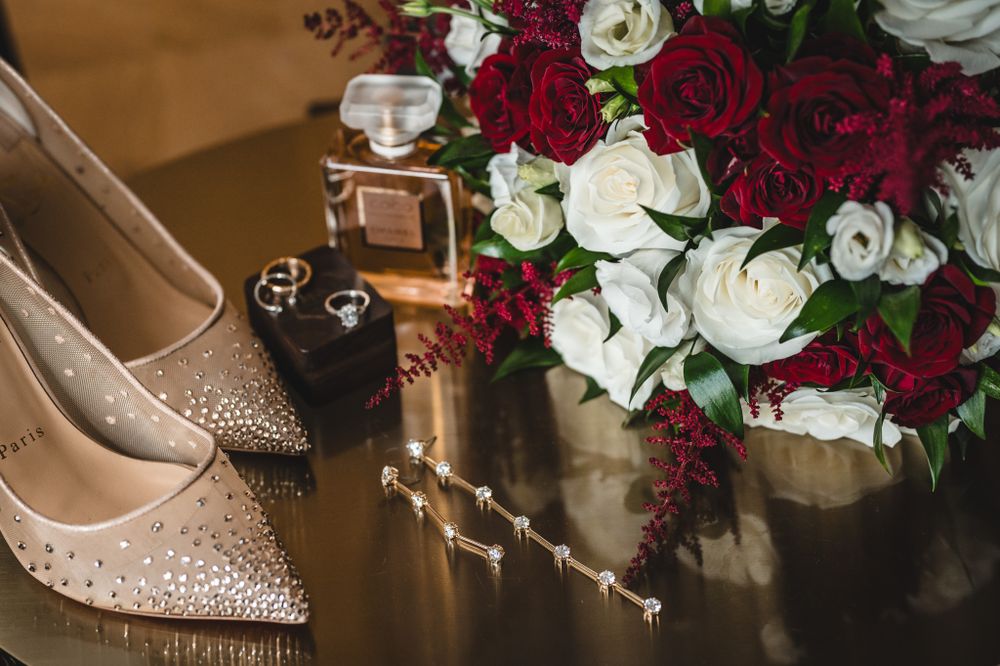 Elegant bridal shoes and floral arrangements with deep red and white roses.