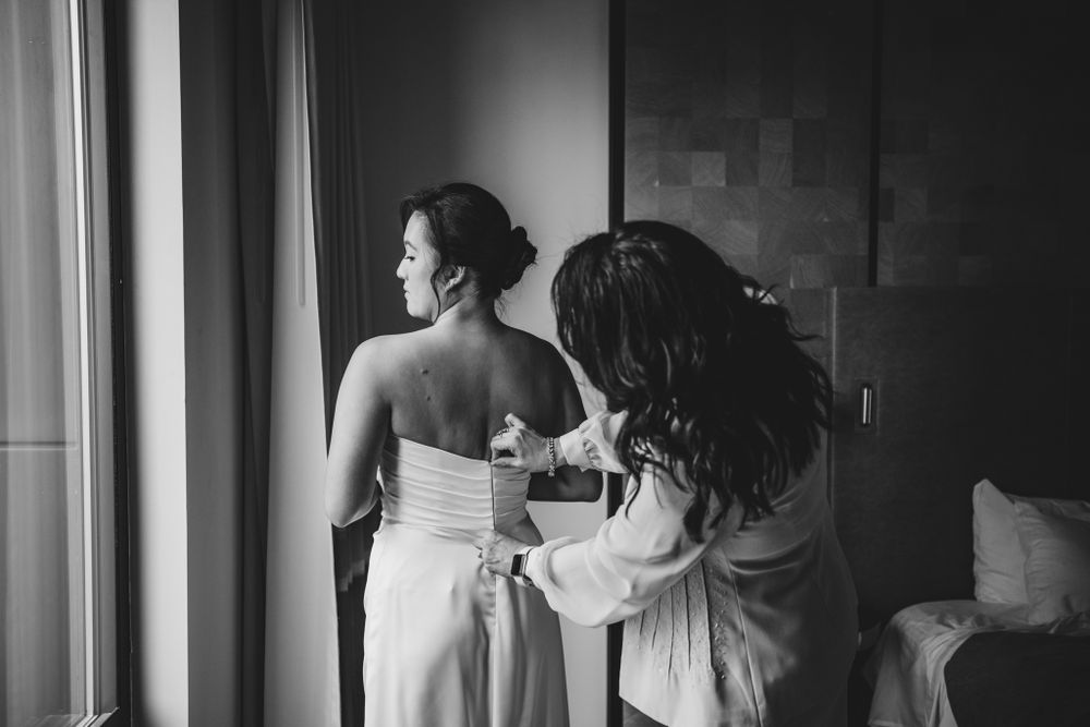 Silhouettes preparing for special occasion in dark room with natural light.