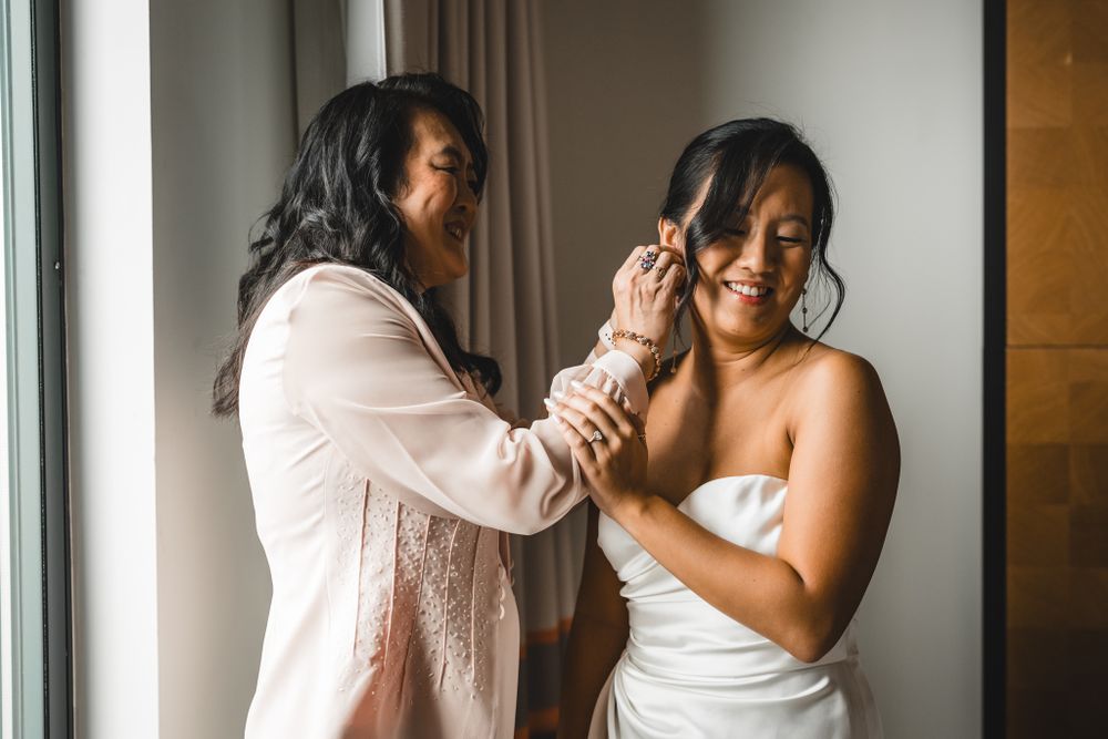 Candid moments captured during wedding preparation by window.