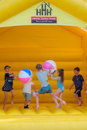 Children playing with beach balls in a yellow bounce house at Hanmer Holiday Homes.