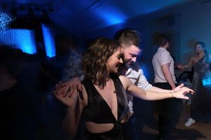 Couple dancing closely at a wedding reception with blue ambient lighting.