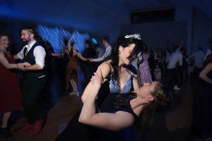 Guests dancing energetically at a wedding reception, with a bride wearing a tiara enjoying the celebration.