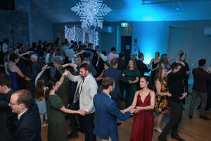 Guests dancing at a formal wedding reception with blue lighting and snowflake chandeliers.