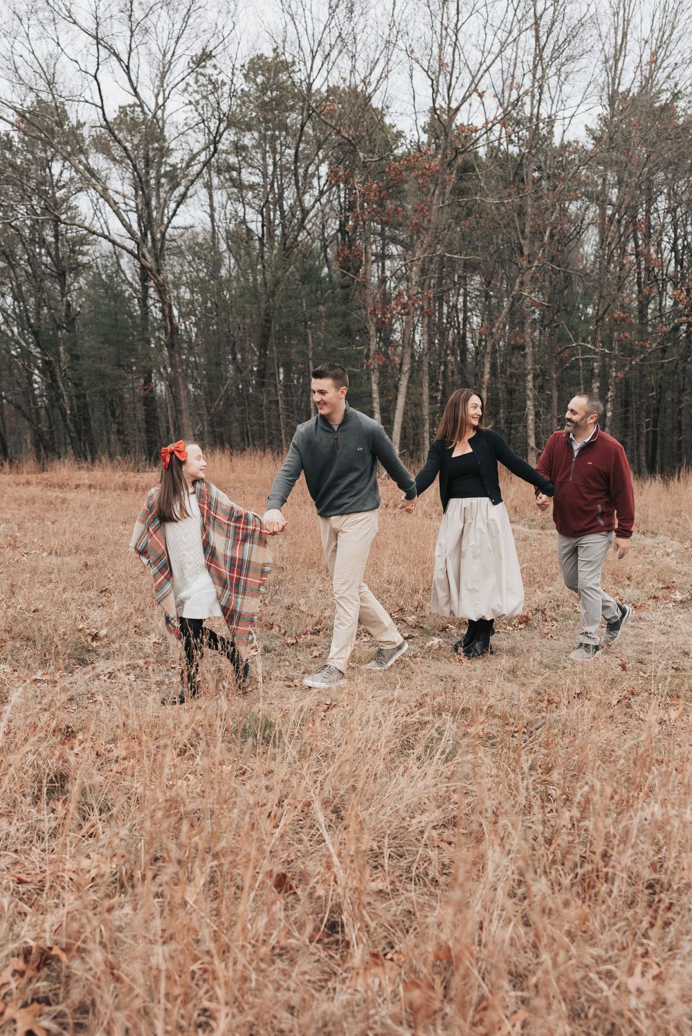 Group walking together through a golden autumn field with tall dried grass and bare trees in the background.