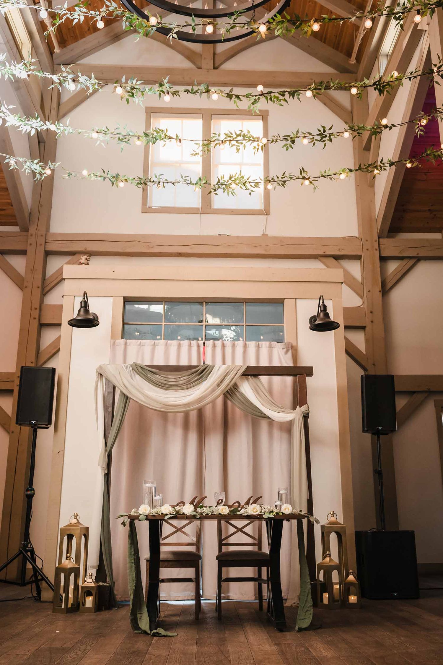 Reception head table setup with greenery, candles, and string lights at Briar Barn Inn indoor wedding venue