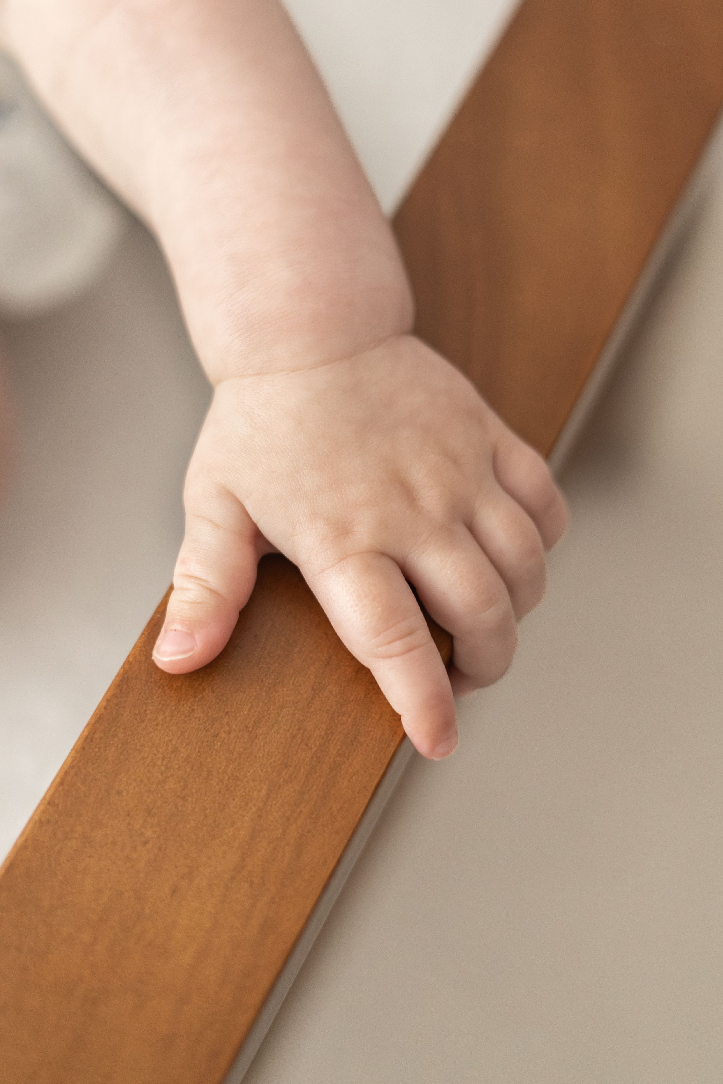 Close-up of a baby's hand gripping the wooden chair, natural relaxed baby birthday photoshoot Nottingham