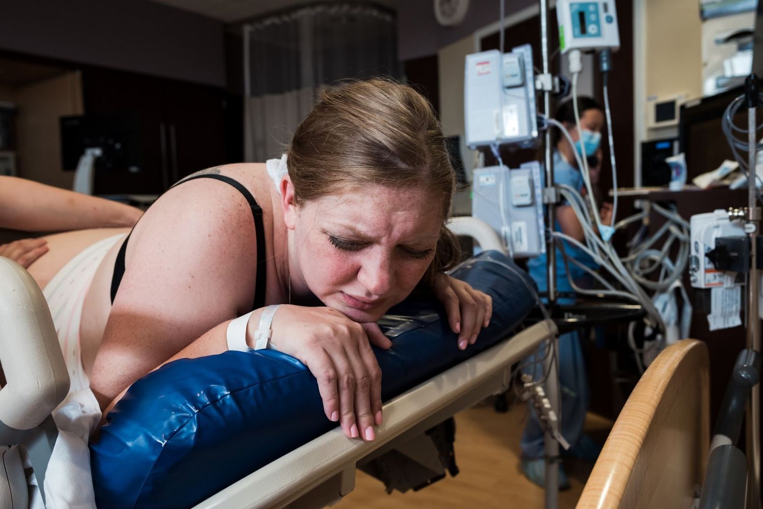 Patient rests on hospital bed while surrounded by medical monitoring equipment.
